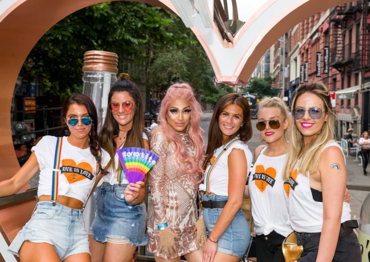 girls posing with drag queen on top of the tito's pride parade float for pride month