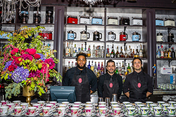 bartenders standing behind a bar covered in tea cups for russell hobbs