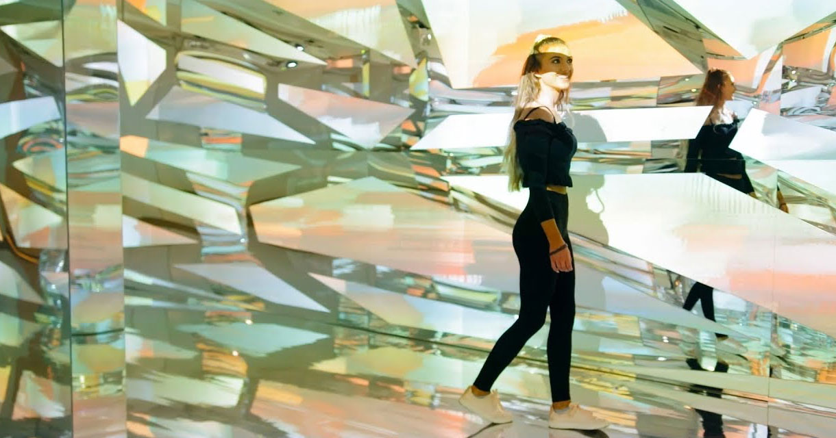 girl posing in a room full of mirrors for immersive experiences