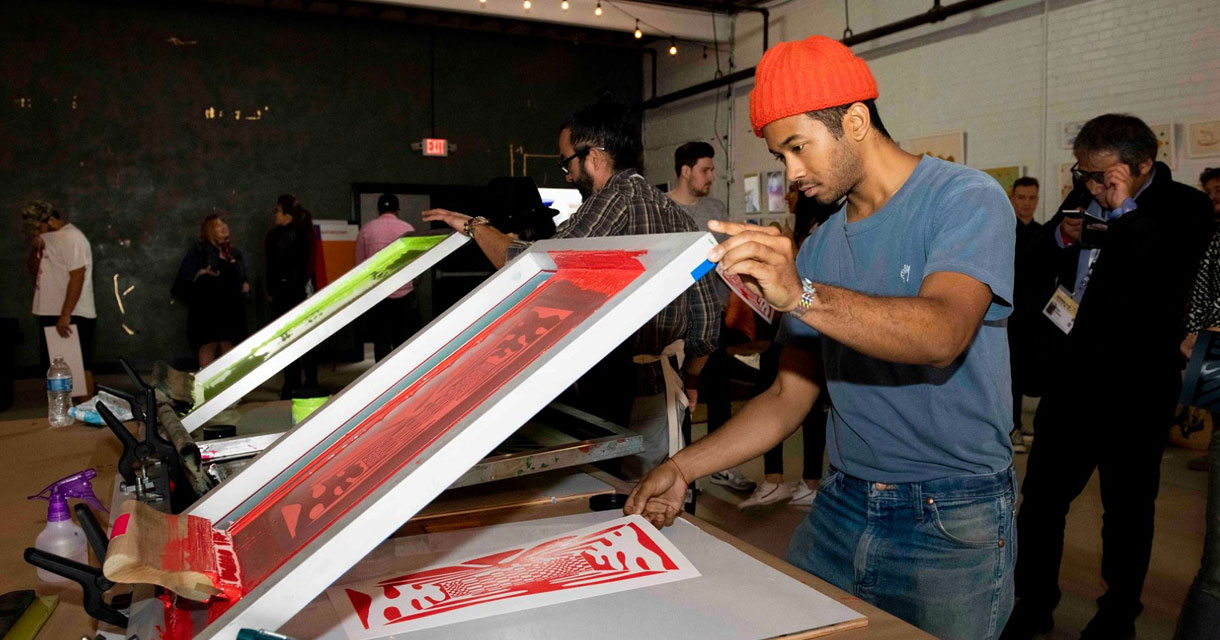 man screenprinting with other screen printing in the background for the SXSW event