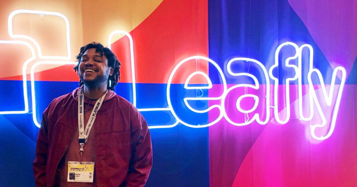 guy smiling in front of a leafly neon light sign for SXSW