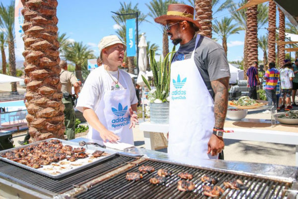 men in adidas sports club aprons grilling meat