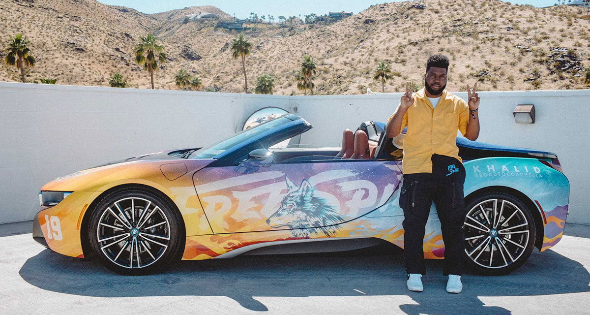 khalid standing in front of a bmw in the desert