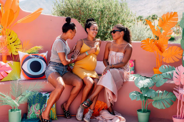 women sitting on a bench surrounded by colorful plants at an instagram coachella pop up experience