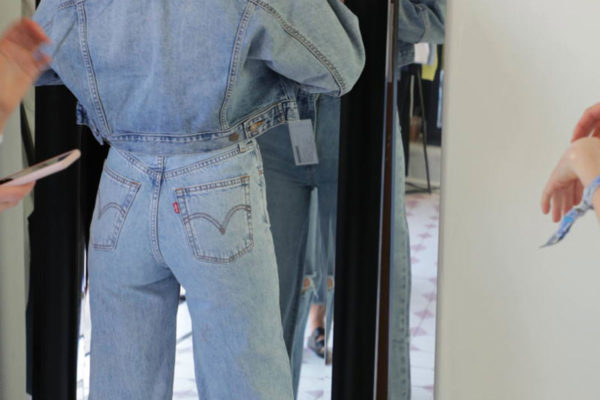 women looking in the mirror wearing levi jeans and a jean jacket