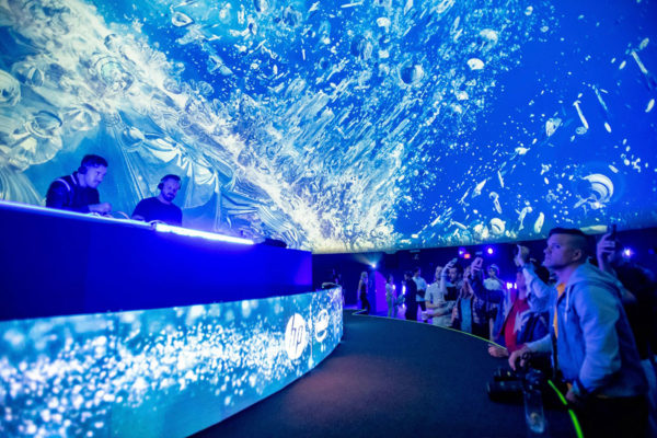 dj's performing in an under water display with an audience