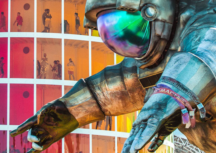 large astronut statue in front of a colorful building with people inside for Immersive Art Installations