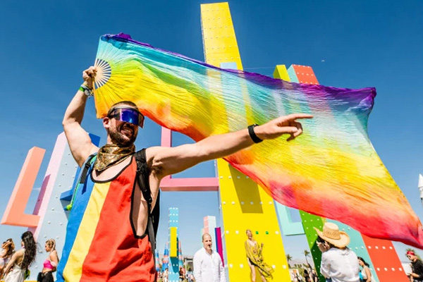 man dancing with a rainbow flag at coachella