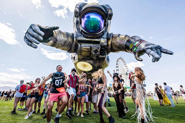 people posing with the poetic kinetics astronaut sculpture at coachella