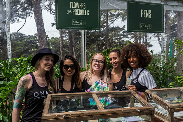 group of ladies at grass lands behind display of cannabis flowers prerolls and pens available because of marijuana laws