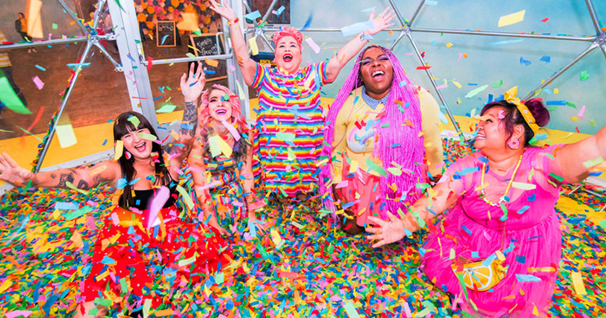 women posing in a pool of rainbow confetti