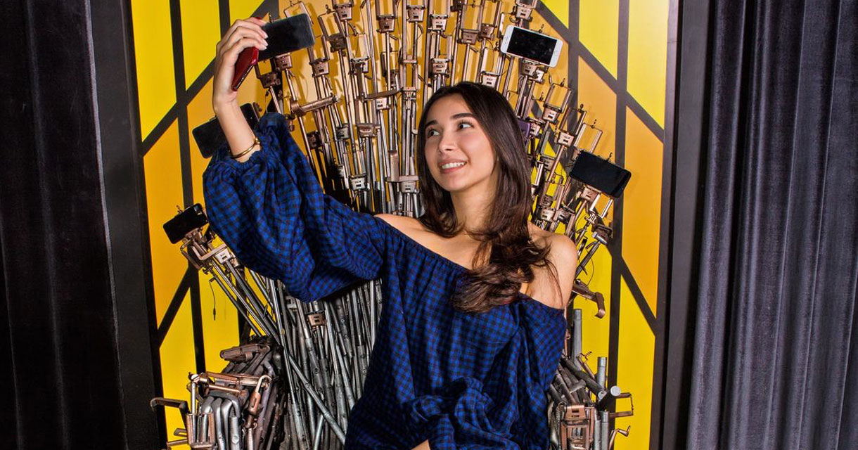 girl sitting on a throne of selfie sticks taking a selfie
