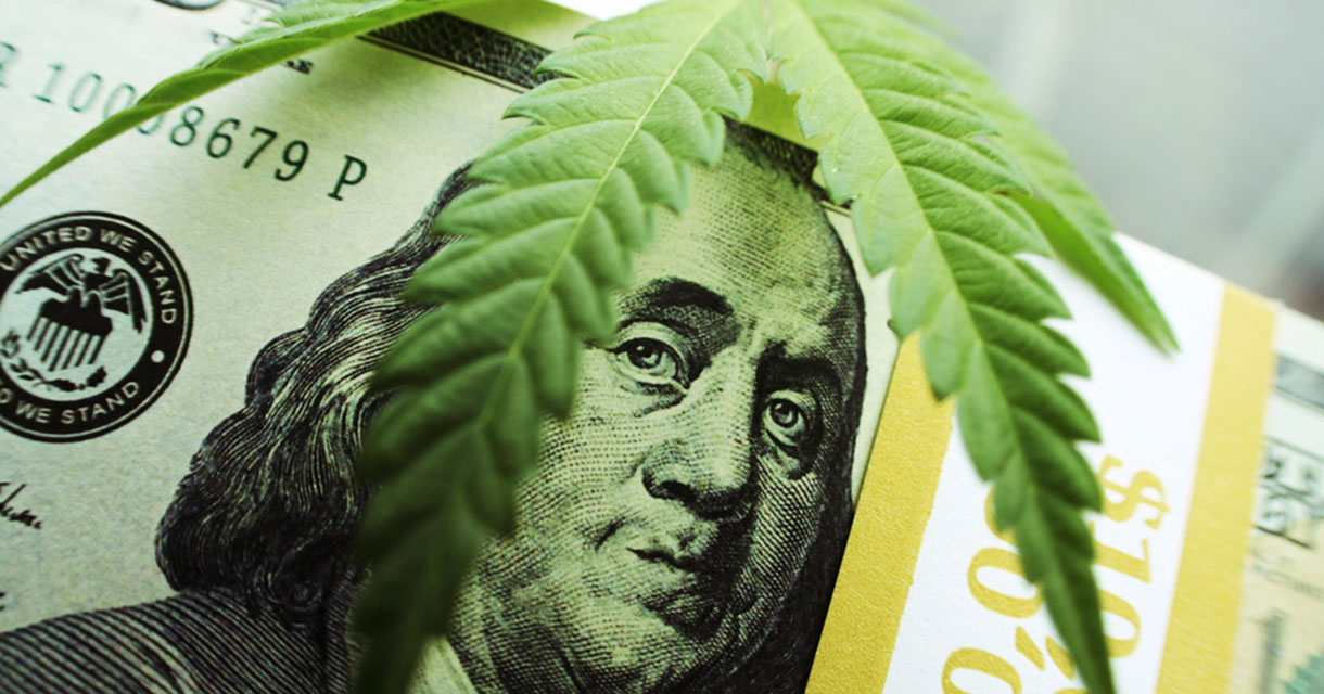 hundred dollar bills stacked under a marijuana leaf signifying marijuana laws