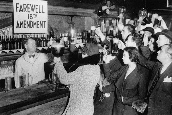 people cheer-sing in a bar with a farewell 18th amendment sign for cannabis and prohibition