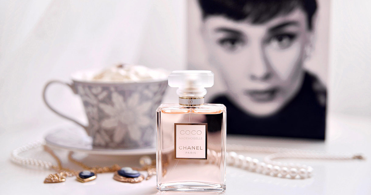 image of chanel bottle perfume, a tea cup and photo of a women in the background for women's history month