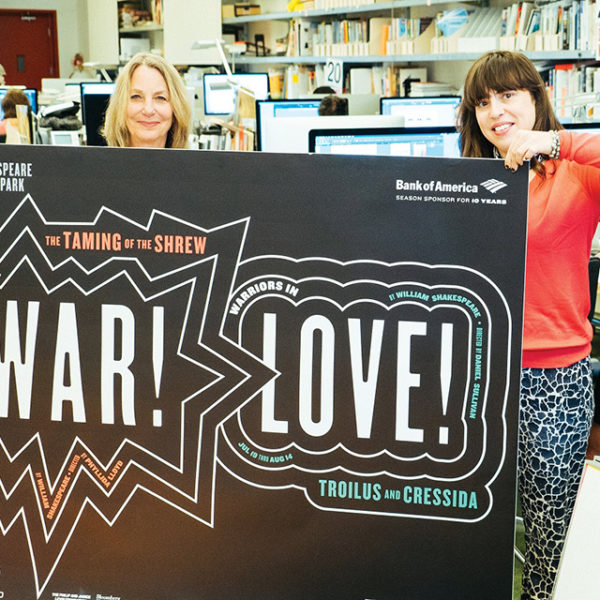 image of graphic designers holding up a sign in an office that says war and love for women's history month